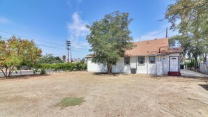 A single-story house with a red-tiled roof, a front porch, and a small yard. - Sunny Hemet Escape w/ Covered Porch & Fire Pit (Hemet)