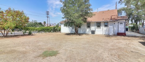 A single-story house with a red-tiled roof, a front porch, and a small yard.