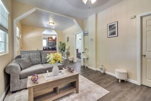 Ein Wohnzimmer mit Sofa, Couchtisch und einer Küche im Hintergrund.