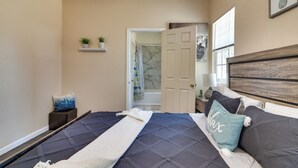 A bedroom with a bed, a nightstand, a window, and a door leading to a bathroom. - Sunny Hemet Escape w/ Covered Porch & Fire Pit (Hemet)