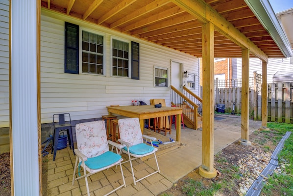 Une terrasse couverte avec une table et des chaises en bois, un petit escalier et une clôture en bois.
