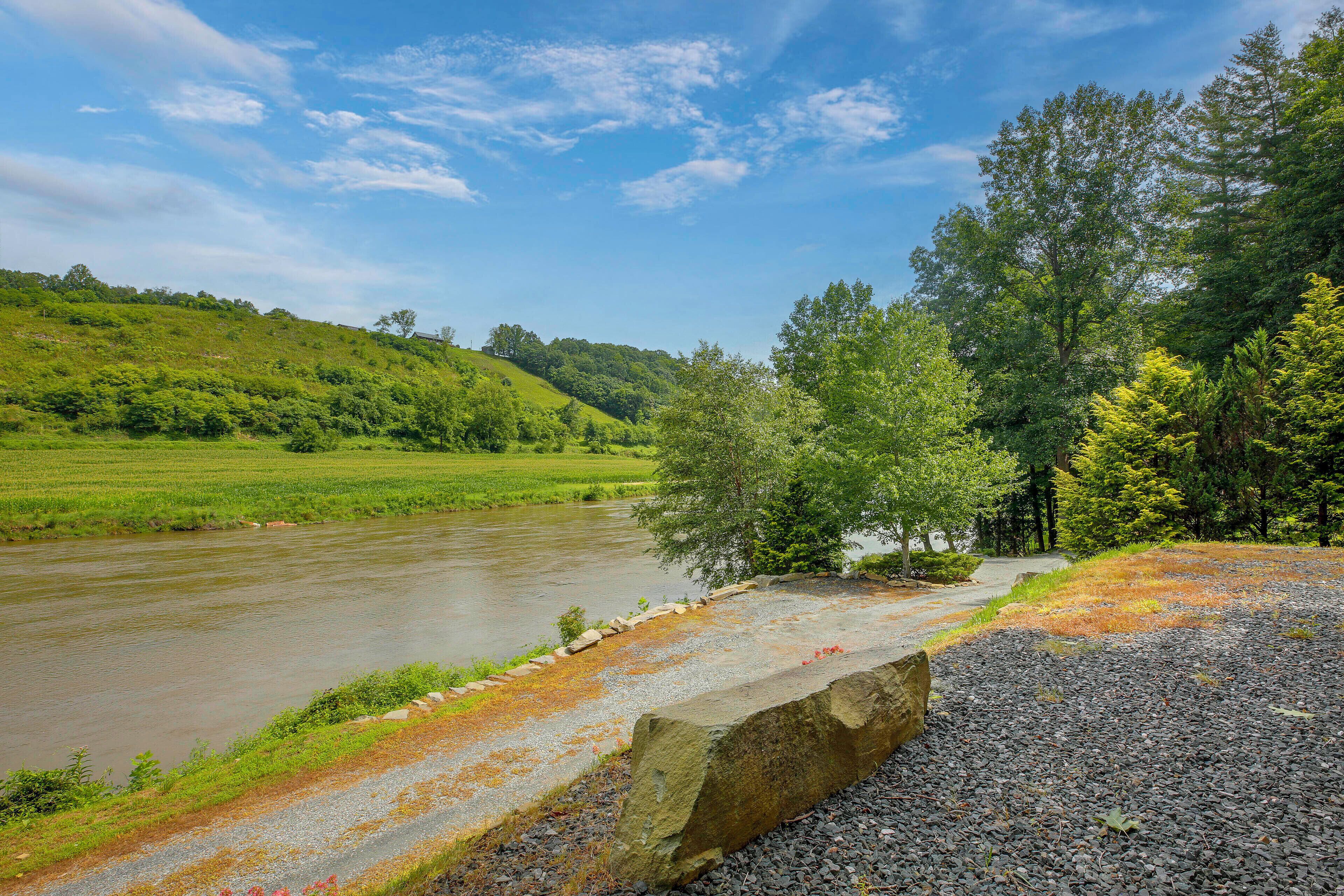 A river with a stone wall and a gravel path alongside.