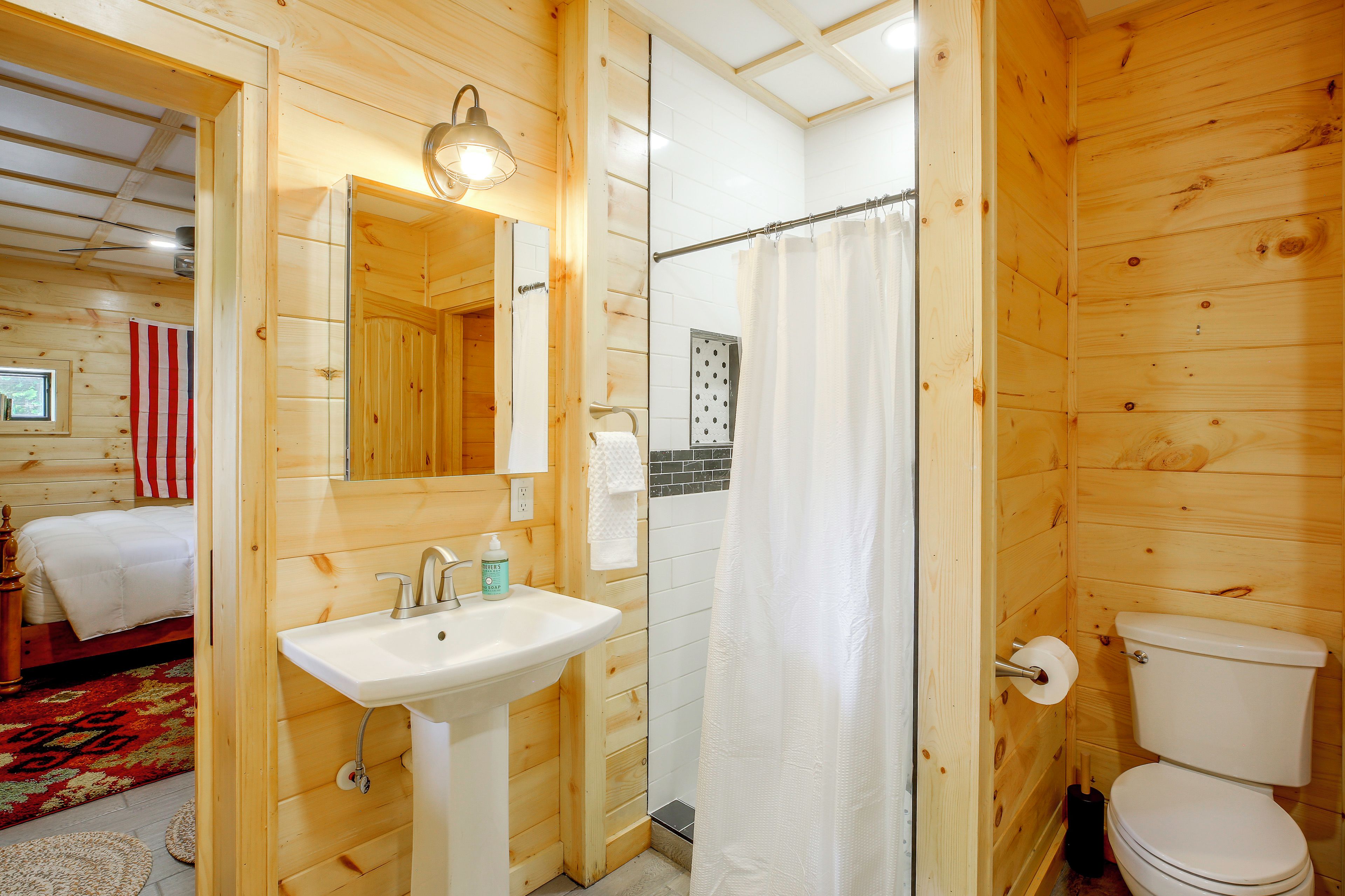 A wooden interior with a bathroom including a sink, toilet, and shower curtain.