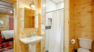 A wooden interior with a bathroom including a sink, toilet, and shower curtain.