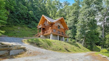 A log cabin with a stone foundation, wooden exterior, and a balcony.