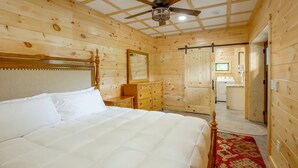 Ein Schlafzimmer mit Holzwänden, einem Bett, einer Kommode und einem Deckenventilator.