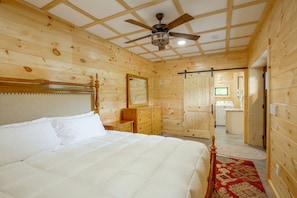 Ein Schlafzimmer mit Holzwänden, einem Bett, einer Kommode und einem Deckenventilator.