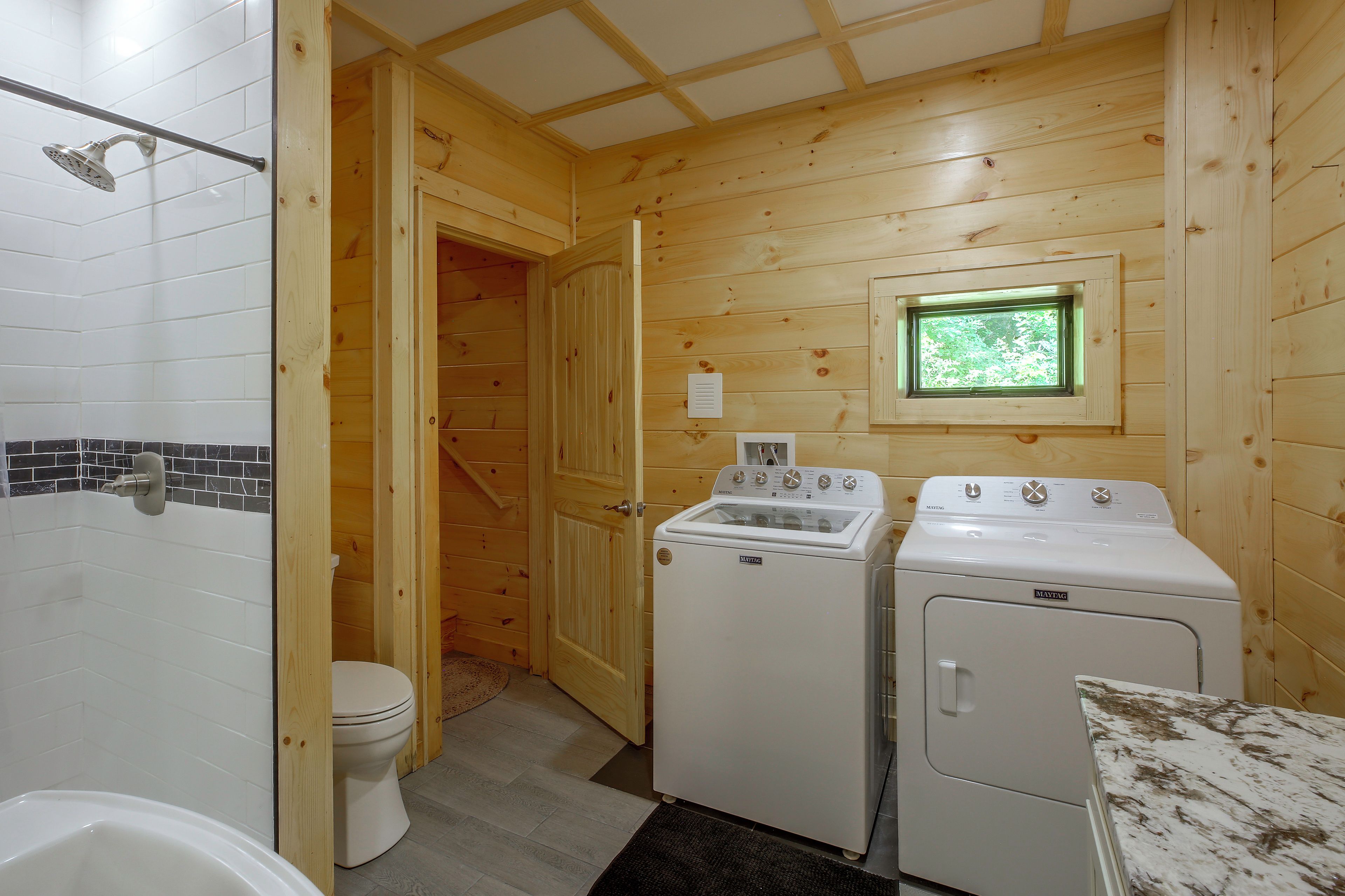 Une petite salle de bain comprenant une douche, des toilettes et un lave-linge.