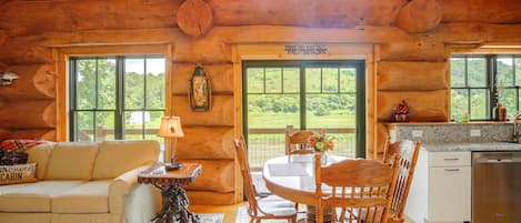 A log cabin interior with a dining area, a sofa, and a kitchen.