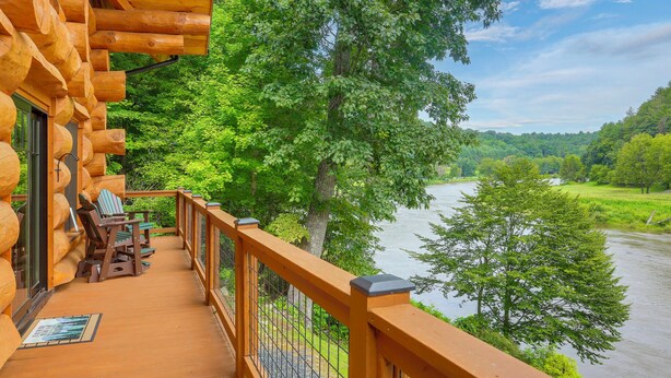 Eine Holzterrasse mit Sitzgelegenheiten und Blick auf einen Fluss.