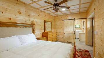 A wooden-paneled bedroom with a bed, dresser, and a ceiling fan.