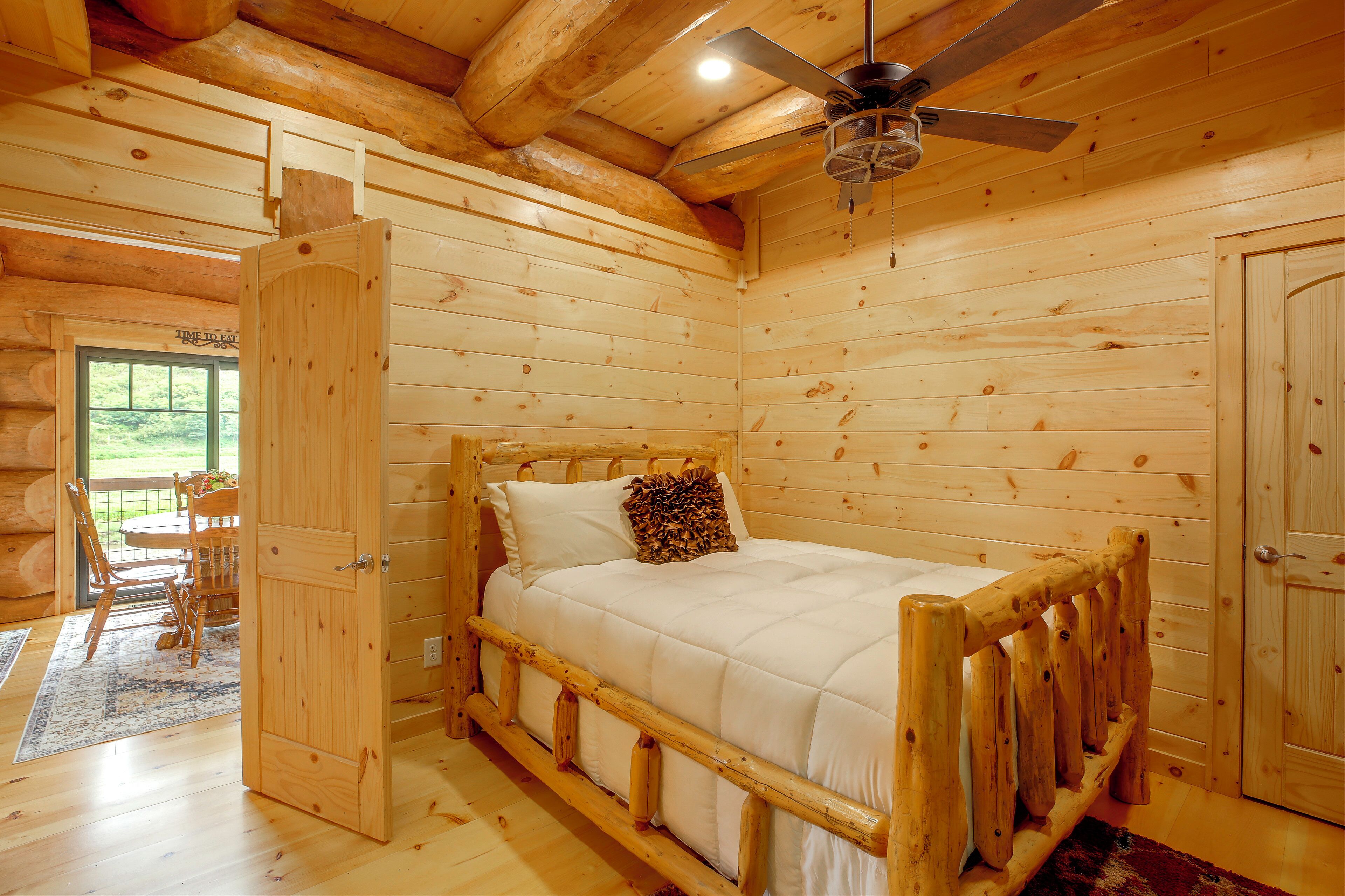 Ein Holzhütten-Innenraum mit einem Bett, einem Esstisch und einem Deckenventilator.