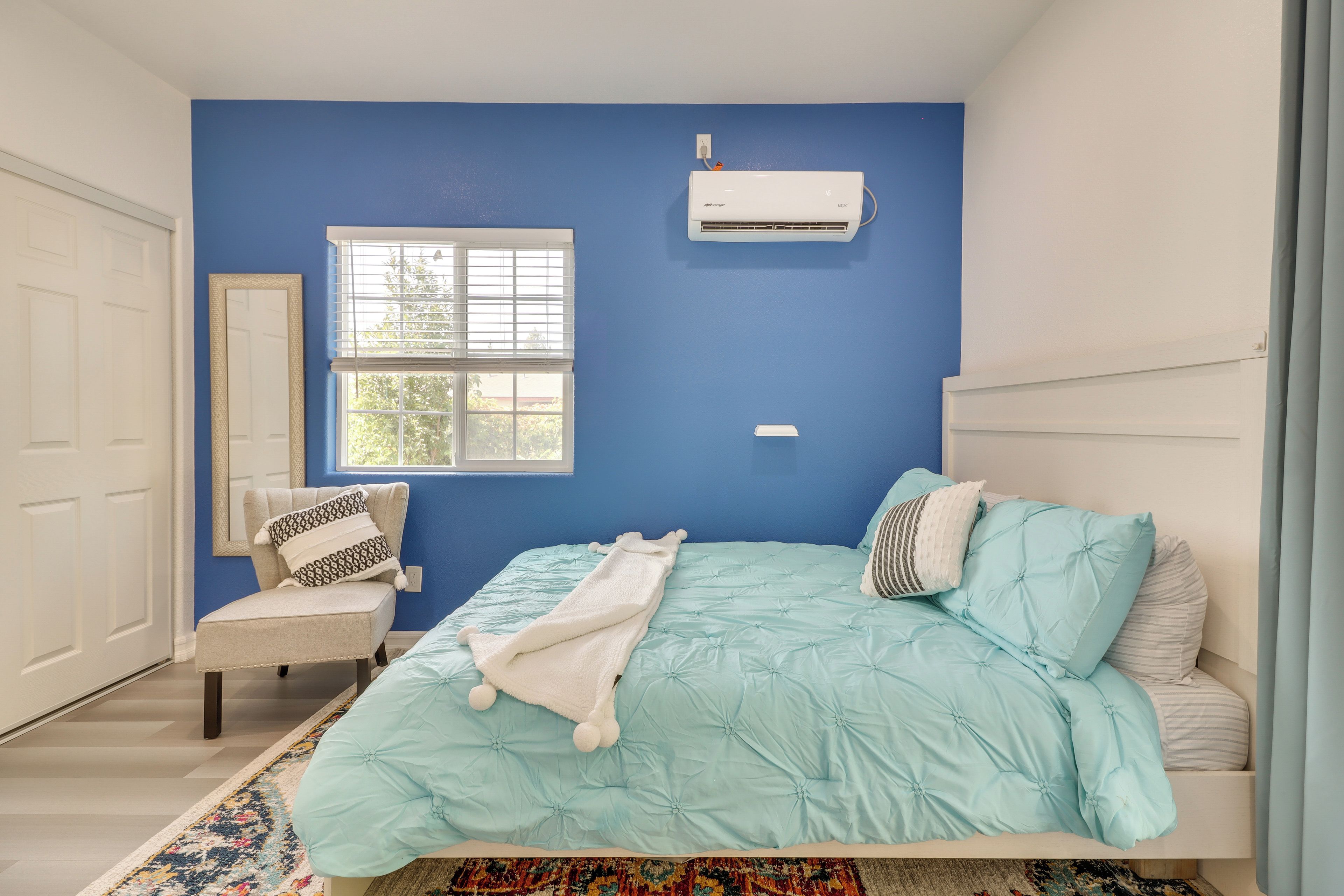 Una camera da letto con un letto, una sedia, una finestra e un condizionatore d'aria.