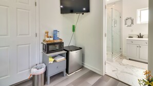 A modern bathroom with a shower, a toilet, a sink, and a television mounted on the wall. - Soaking Tub, Fire Pit! Hemet Studio Suite (Hemet)