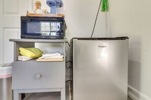 Eine kompakte Küchenzeile mit einem Edelstahlkühlschrank, einer Mikrowelle und einem kleinen Ablagefach mit gefalteten Handtüchern.