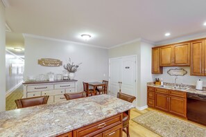 A kitchen with wooden cabinets, a granite countertop, and a dining area with chairs.