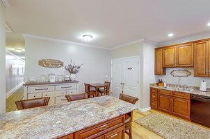A kitchen with wooden cabinets, a granite countertop, and a dining area with chairs.