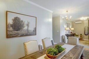 Un comedor con una mesa, sillas, una araña y un cuadro en la pared.
