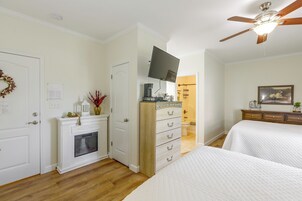 Un dormitorio con cama, cómoda, televisor y ventilador de techo.
