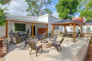 Un área de patio al aire libre con mobiliario de mimbre, una chimenea y un pérgola.