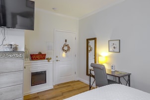 Habitación de hotel con cama, escritorio y silla, televisión, chimenea y puerta decorada con un adorno.