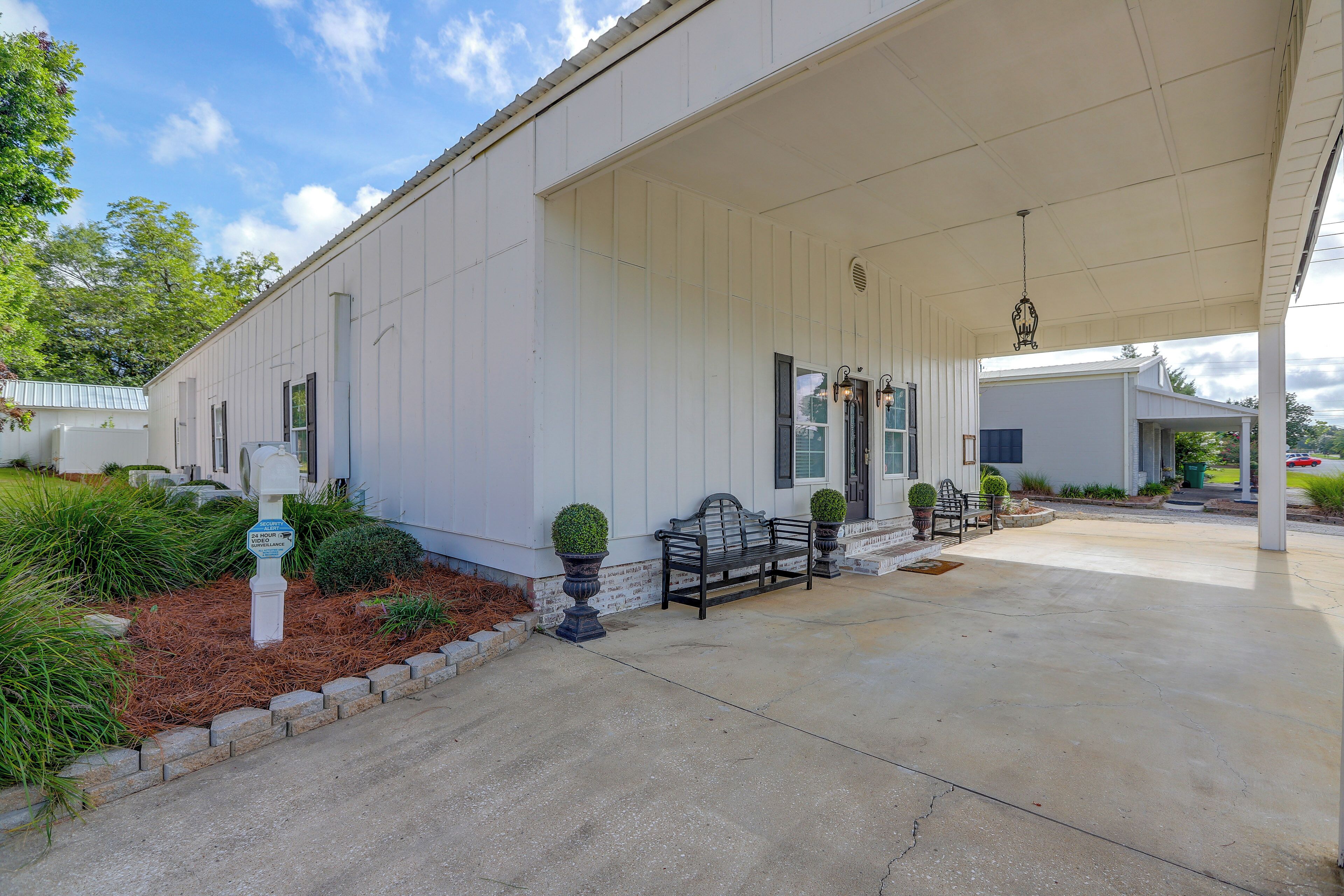 A covered porch with a bench, a mailbox, and a security camera.
