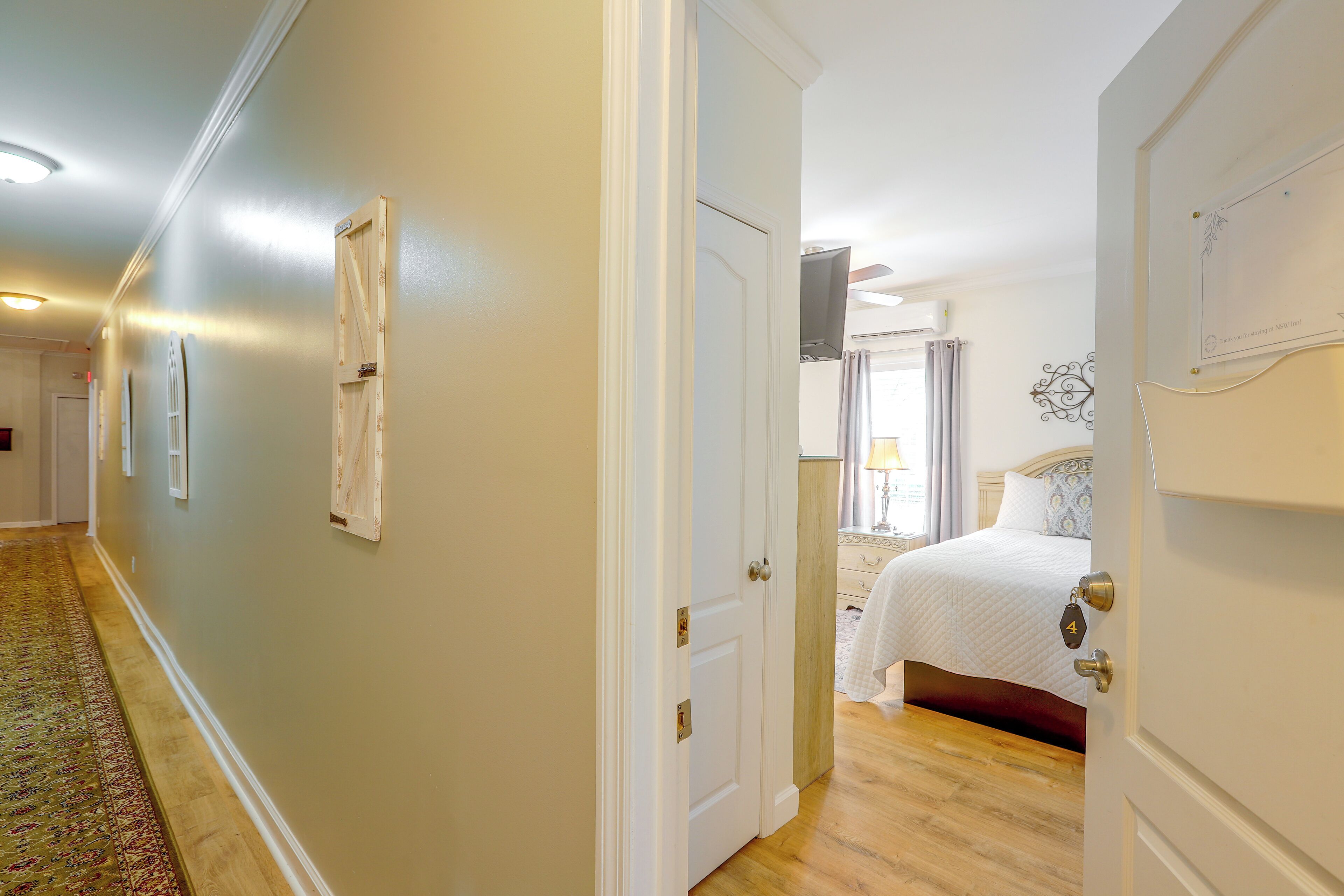 A hotel room with a bed, a nightstand, a lamp, and a window with curtains.