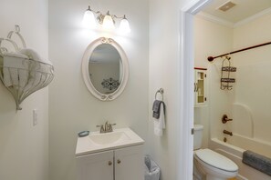 A bathroom with a white sink, a mirror, a towel rack, and a shower area.
