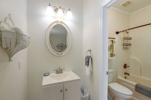 Un baño con lavamanos blanco, espejo, toallero y zona de ducha.