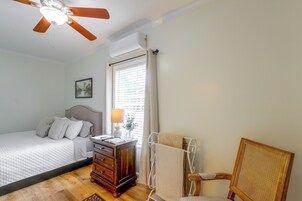 Un dormitorio con cama, cómoda, silla y ventilador de techo.