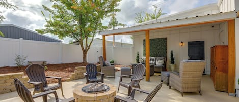 An outdoor patio area with a fire pit, multiple chairs, and a covered seating area.