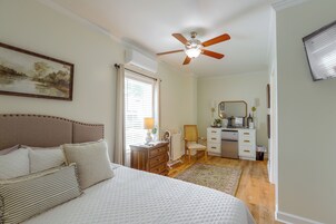 Un dormitorio con una cama, ventilador de techo, cómoda, silla y escritorio.