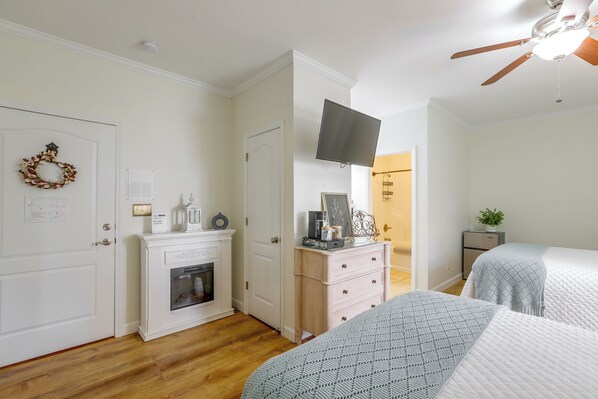 A bedroom with a fireplace, a television mounted on the wall, and a bed with a patterned blanket.