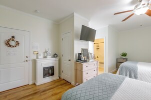Un dormitorio con chimenea, televisor montado en la pared y cama con colcha estampada.