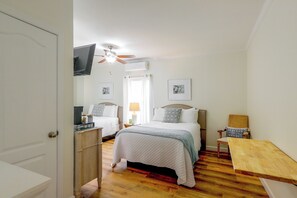 Un dormitorio con dos camas, un ventilador de techo y un televisor montado en la pared.