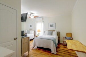 Un dormitorio con dos camas, un ventilador de techo y un televisor montado en la pared.