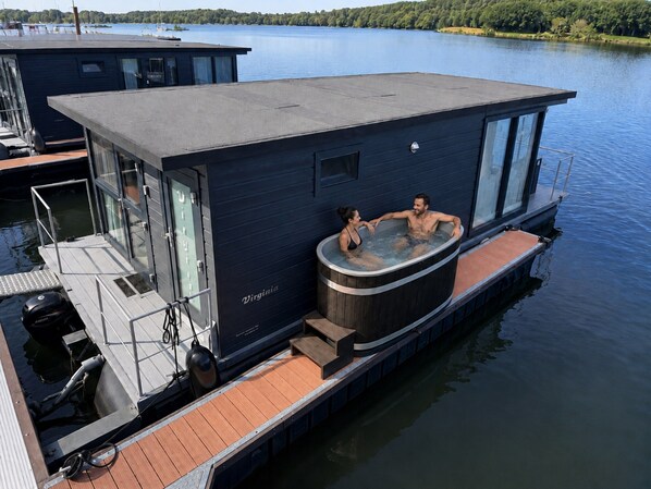 Una casa flotante con un jacuzzi y un muelle.