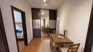 A room with a wooden dining table, chairs, a rug, and a view through a doorway. - Large Family Apartment for 7 - Central BA (Bratislava)