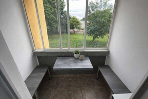 A balcony with a view of a green landscape, a potted plant, and a small table.