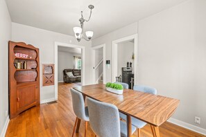 A dining room with a wooden table, grey chairs, and a 'MERRY' sign on a wooden cabinet. - Roadmap Lodging: 3BR Near Columbus Regional Health (Columbus)