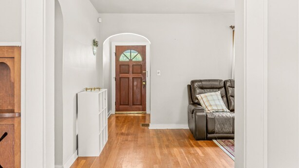 A hallway with a wooden door, a white cabinet, and a leather sofa with a plaid cushion. - Roadmap Lodging: Near Columbus Regional Health, 3BR Monthly, Pet OK (Columbus)