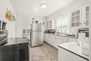 A kitchen with a refrigerator, stove, and various appliances. - Roadmap Lodging: 3BR Near Columbus Regional Health (Columbus)
