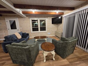Ein gemütliches Wohnzimmer mit Holzboden, einem an der Wand montierten Fernseher und einer Tür zu einer Treppe.
