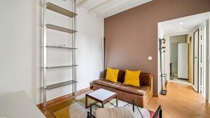 Un salon comprenant un canapé, une table basse et une étagère en métal.