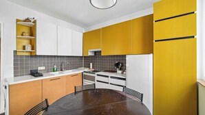 A modern kitchen with a round dining table, built-in cabinets, and a refrigerator. - Charming Fully Equipped 1BR - Near Paris (Boulogne-Billancourt)