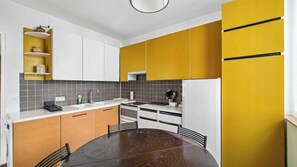 Eine moderne Küche mit einem runden Esstisch, Einbauküchenschränken und einem Kühlschrank.