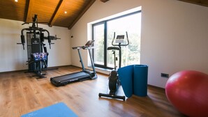 Une salle de sport équipée de matériel d’exercice, d’un tapis de course et d’une grande fenêtre.