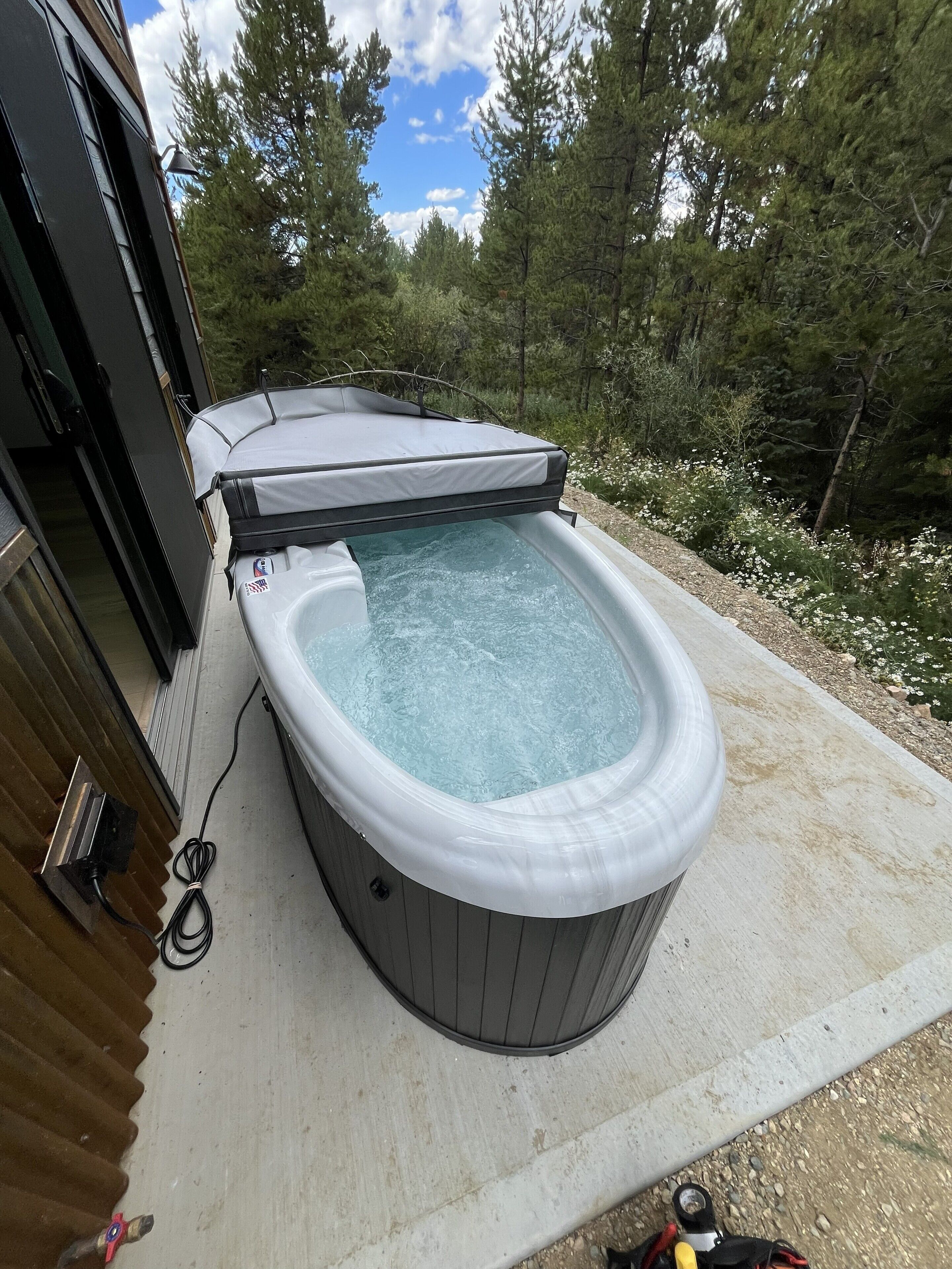 A hot tub with a cover, connected to a building with a door and windows.