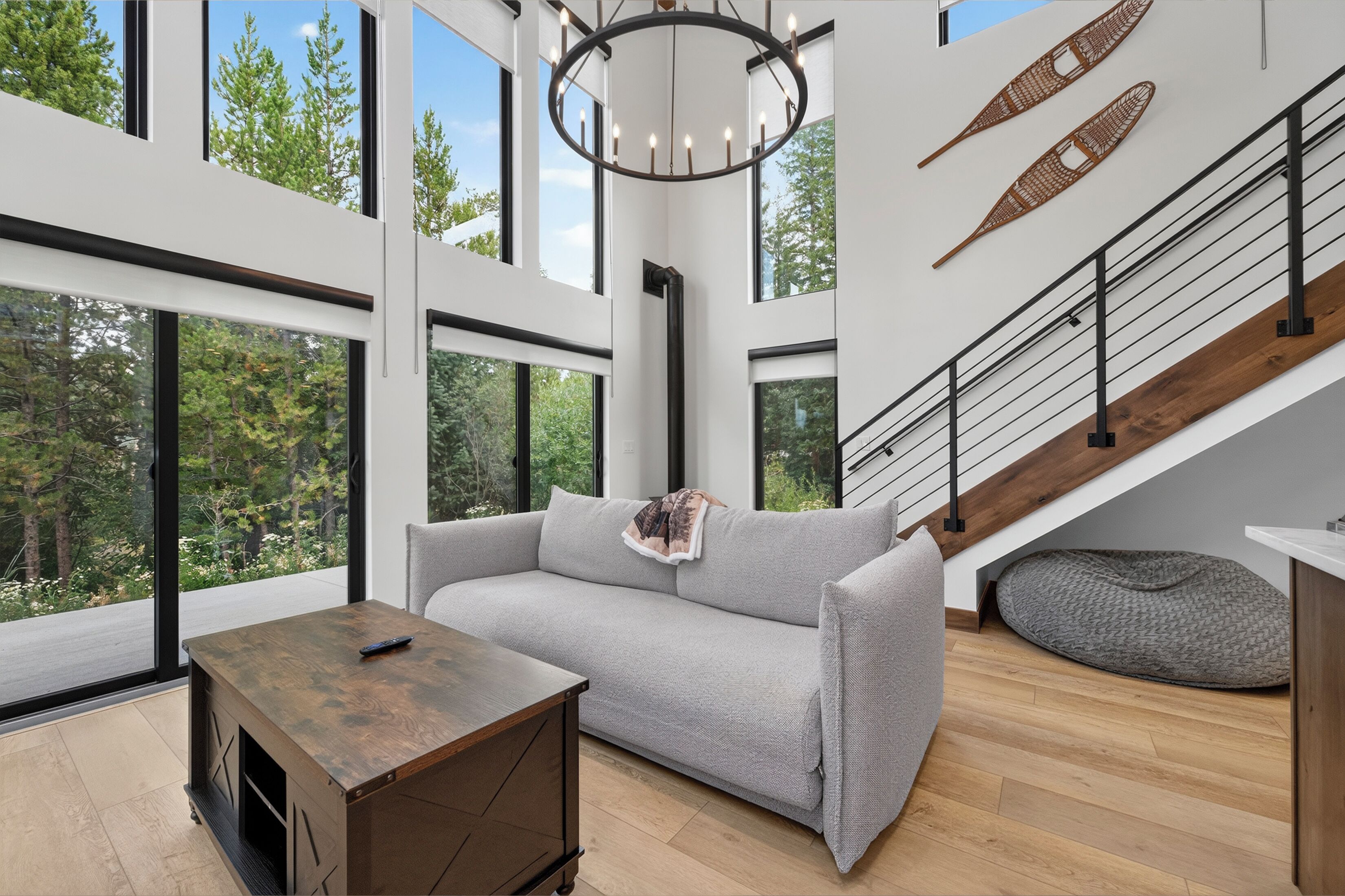A modern living room with a grey sofa, a wooden coffee table, and a staircase with a wooden finish.