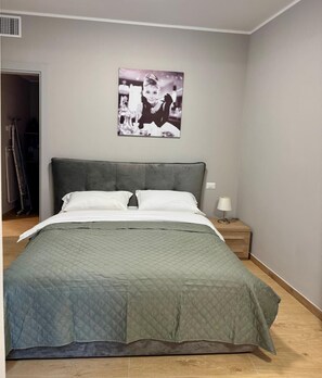 Un dormitorio con una cama, una mesita de noche, una lámpara y un cuadro en la pared.